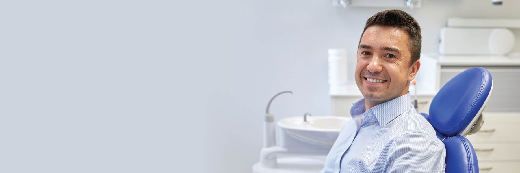 Smiling man sitting in a dental chair at a modern cosmetic dentistry office